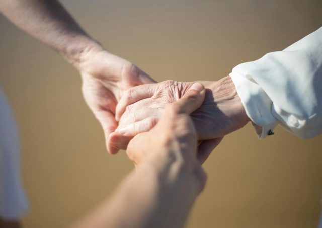 Gentle close-up of intergenerational hands holding, symbolizing connection and care.