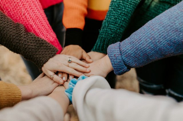 group stacking hands in colorful sweaters